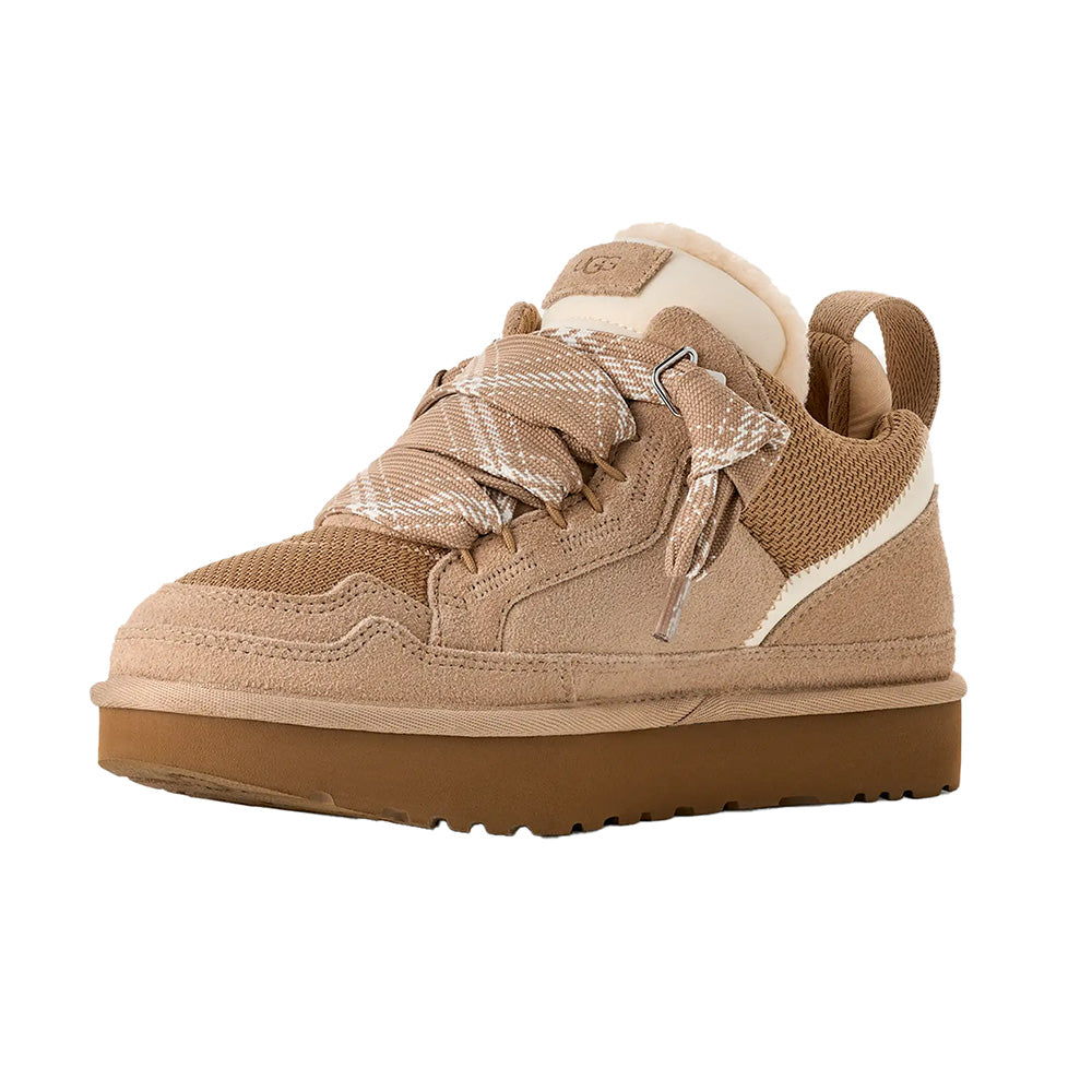 Sand UGG low-top sneaker, left foot view, suede and mesh, cream sole, decorative strap, UGG logo.
