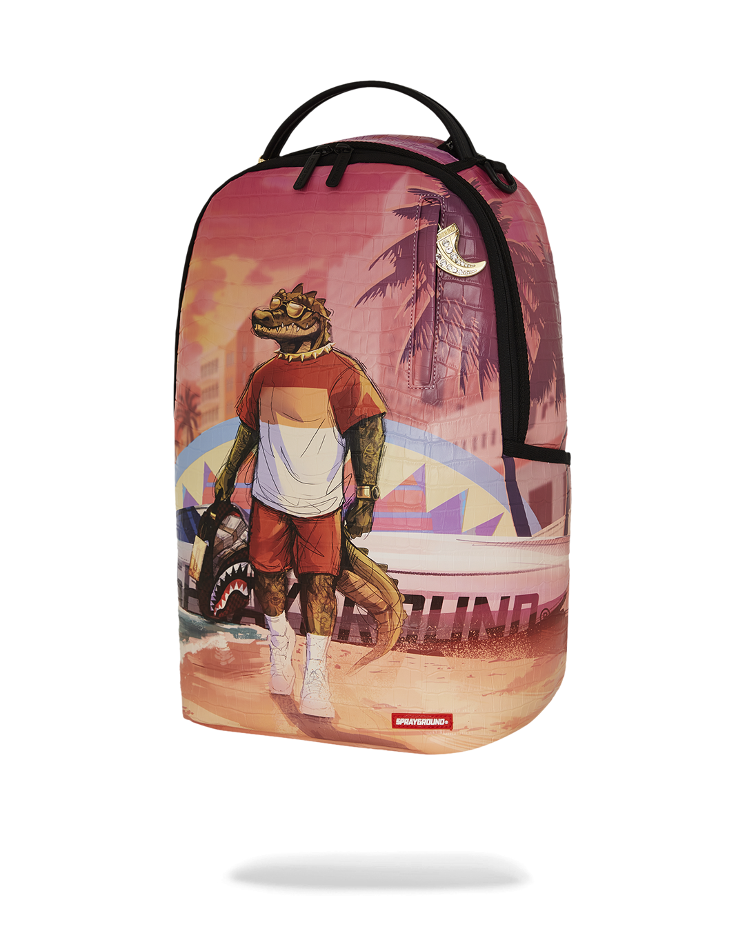 A vibrant Sprayground backpack featuring a graphic of a cool, anthropomorphic alligator standing on a beach. The alligator, who is holding a black Sprayground bag, wears a striped white and red shirt, red shorts, and sunglasses. The backdrop is a beach sunset with palm trees, a cityscape, and a surf van with a shark mouth design. The entire backpack has a subtle crocodile-skin texture and a small gold charm is visible near the top handle.