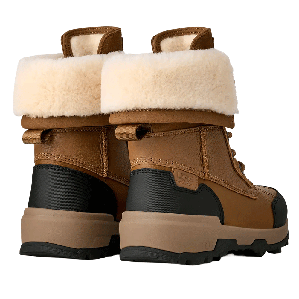 Rear view of a pair of UGG Kid's waterproof brown winter boots, showcasing the thick cream shearling cuff, the durable black and brown heel panel, and the layered traction sole.