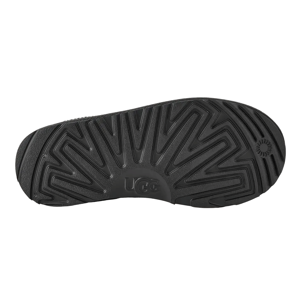 Bottom view of the black Sugarcane EVA or Treadlite by UGG outsole of the Kids' Tasman slipper, showing the repeating UGG logo tread and the deep traction pattern for indoor and outdoor wear.