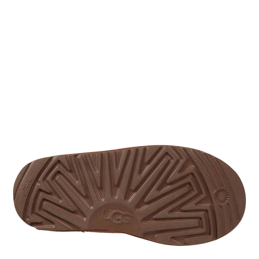 Bottomview of the brown rubber outsole of the UGG Kids Tasman slipper. The sole features a molded zig-zag tread pattern with the UGG logo embossed in the center.