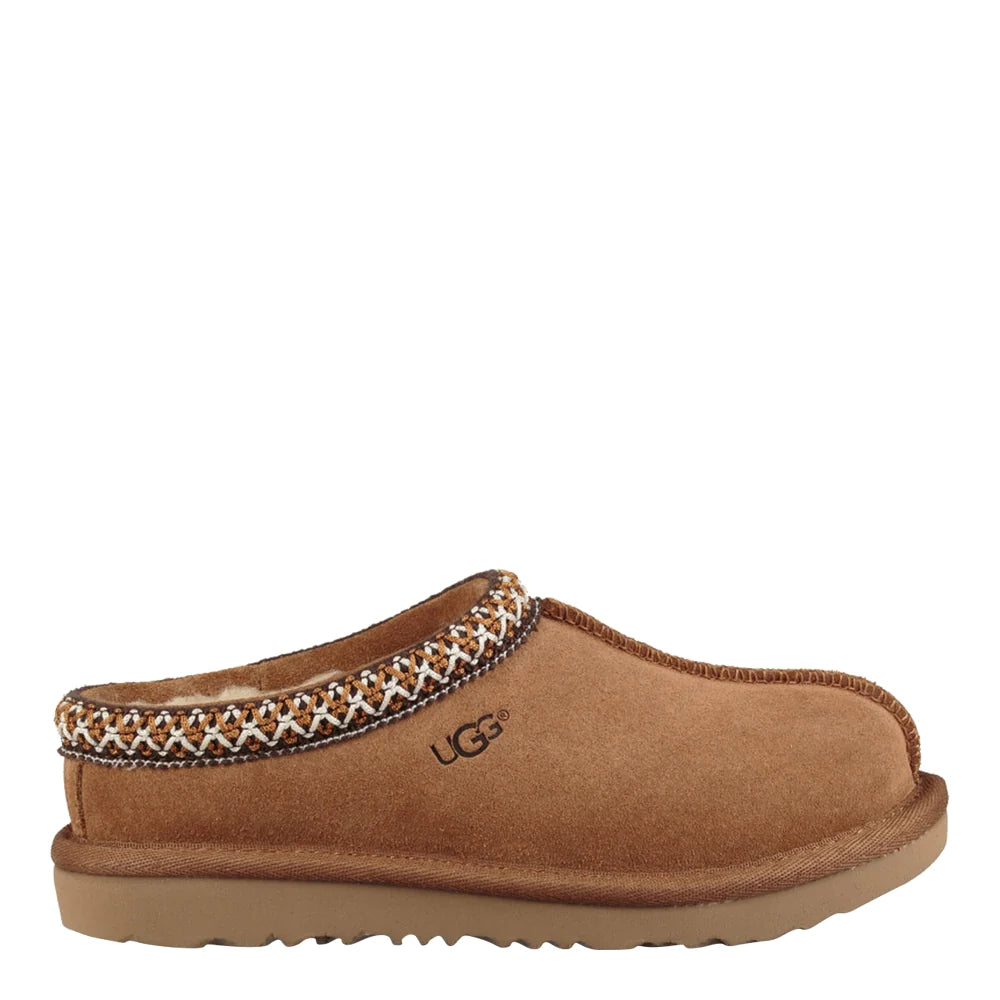 Side view of a single UGG Kids Tasman slipper in chestnut. The shoe features a rich brown suede upper, a light brown Tredlite outsole, and a decorative cream and brown braided Tasman stitch detail around the collar. The UGG logo is embossed on the side.