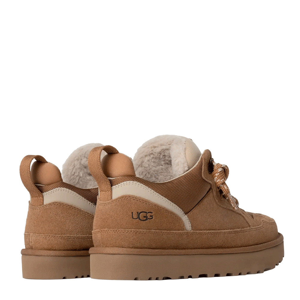 Rear view of a pair of low-top UGG shoes in chestnut suede, highlighting the cream plush interior lining, the UGG logo stamped on the heel, and the pull tabs at the back collar.