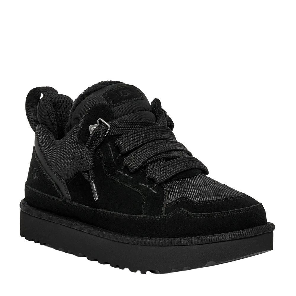 Front perspective view of a single black UGG low-top shoe, featuring a blend of black suede and textured mesh on the upper, wide black ribbon laces, and a thick black platform sole with a pronounced lug tread.