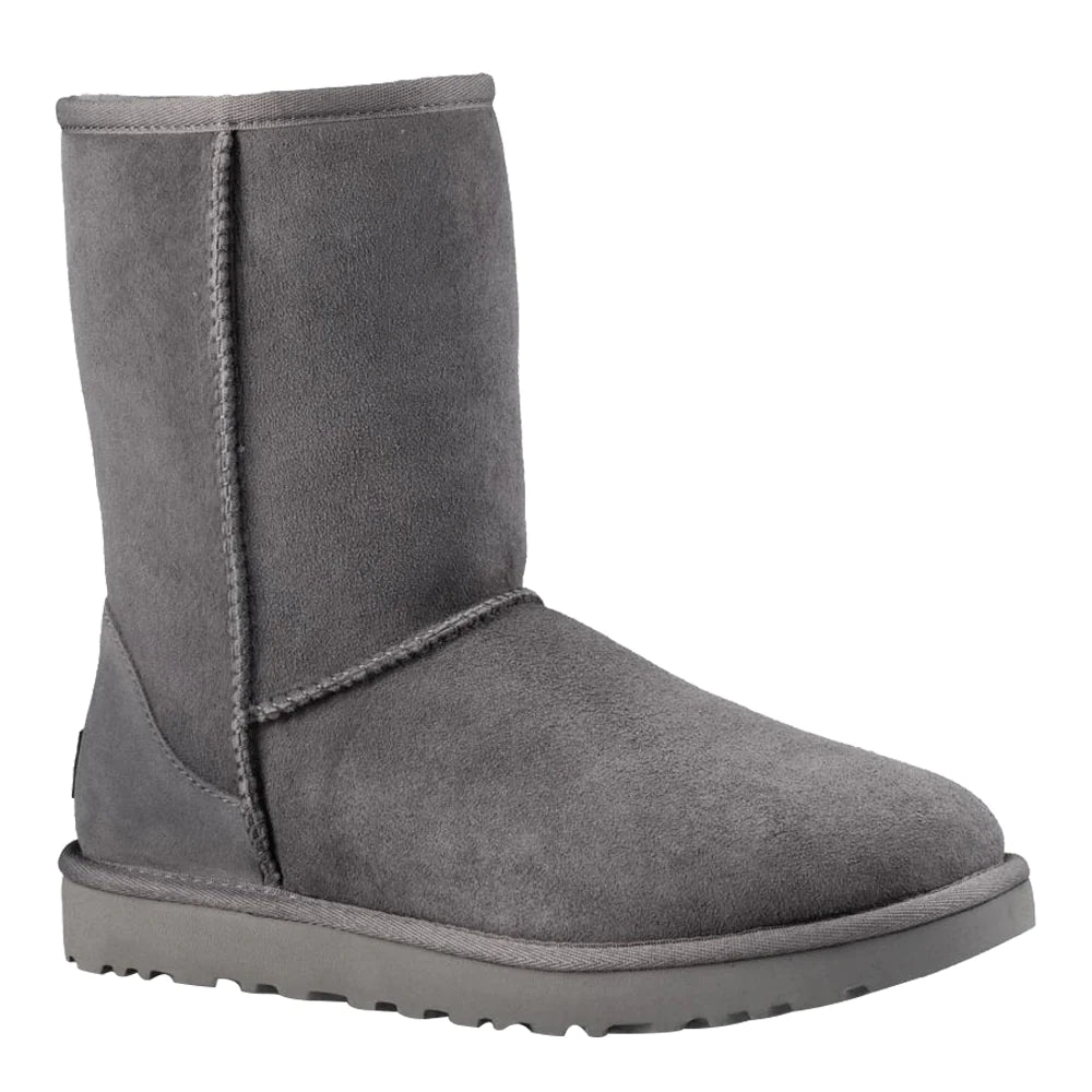 Angled side-view of a single UGG Women's Classic Short II boot in grey suede. The boot shows the full mid-calf shaft, overlock stitching, and the textured grey sole, with a slight view toward the toe.