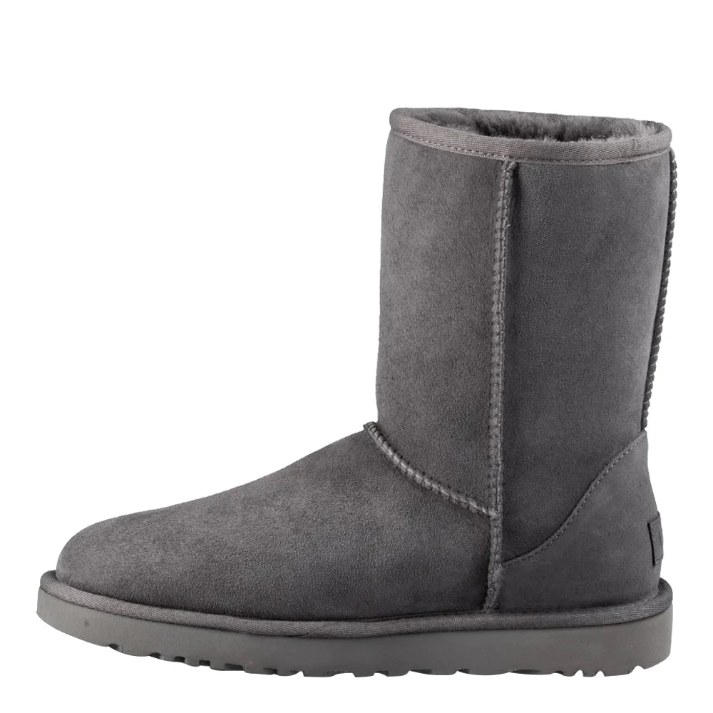 Side-view Of UGG Women's Classic Short II boot in dark grey suede. The boot shows the tall shaft, signature braided stitching, and a sliver of the dark grey wool lining visible at the cuff.