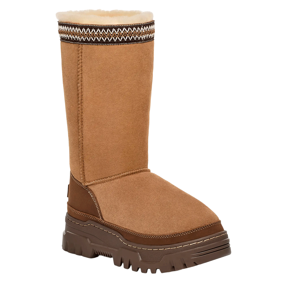 Front view of the tall UGG Classic Tall TrailGazer boot in Chestnut suede, showcasing the tall shaft, the decorative UGGbraid detail around the cuff, and the substantial brown platform sole with visible stitching.