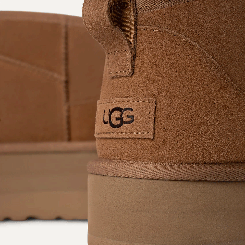 Close-up on the heel of a Chestnut UGG boot, showing the logo tag and the top of the Sugarcane EVA Treadlite platform sole.