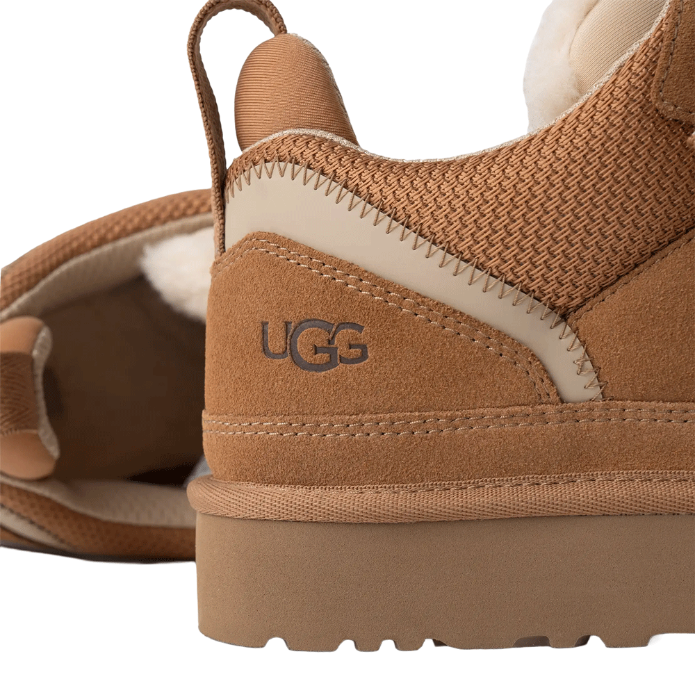 A detailed close-up of the heel of the UGG Lowmel sneaker in chestnut, clearly showing the embossed UGG logo on the suede, the mesh collar, the webbing heel strap, and the thick Sugarcane EVA sole