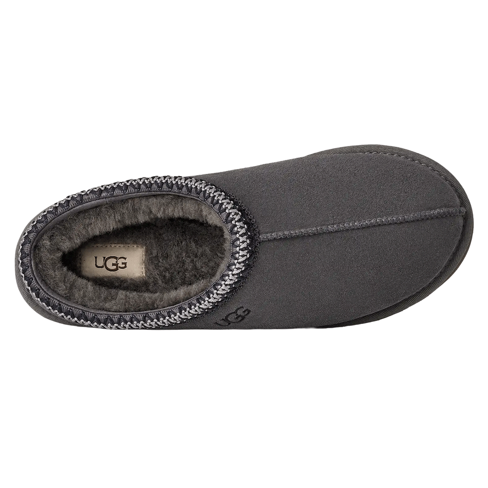 Overhead view of the dark gray UGG Tasman II slipper. The image highlights the cozy dark gray sheepskin lining and insole, the white internal UGG logo tag, and the gray and black UGGbraid trim around the collar.