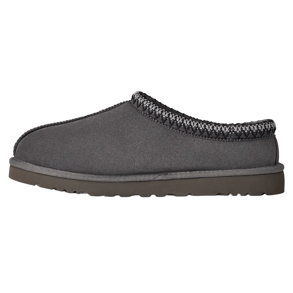 Side profile of the dark gray UGG Tasman II slipper. It has a suede upper, dark gray Sugarcane EVA outsole, and the signature gray and black UGGbraid trim around the collar.