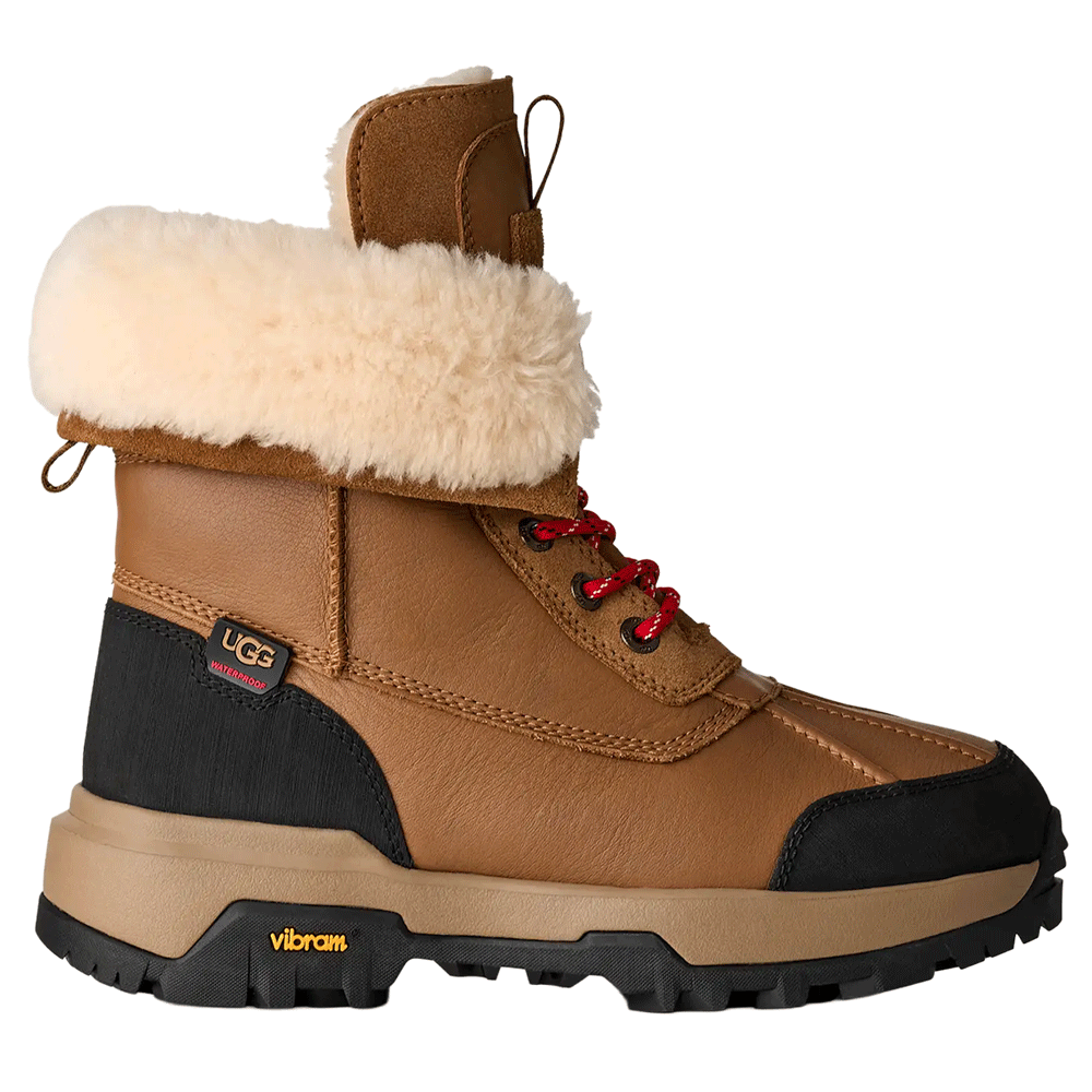 Side view of the Chestnut UGG Adirondack Boot XXV, featuring a waterproof leather upper with red speckled laces, a cream-colored fur cuff, black suede heel panel, and a rugged black and beige Vibram ICETREK outsole.
