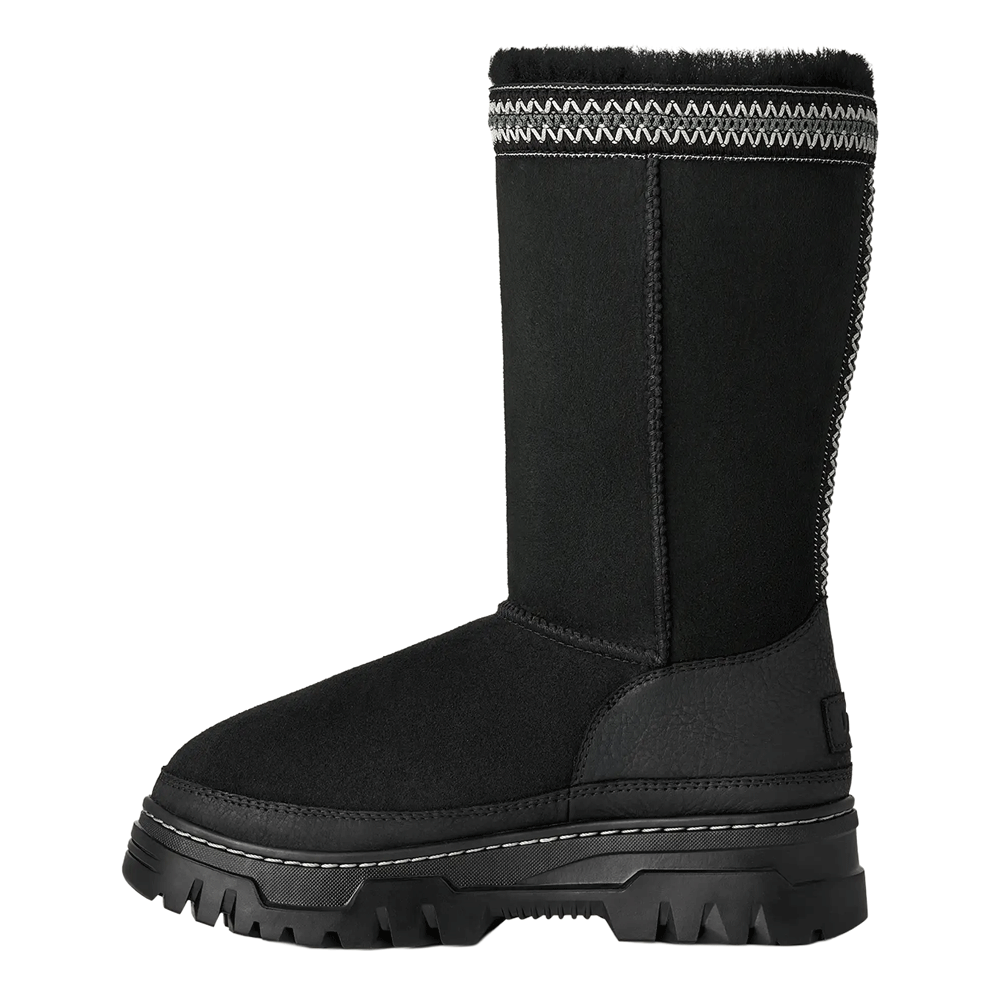 Front perspective view of a single black UGG low-top shoe, featuring a blend of black suede and textured mesh on the upper, wide black ribbon laces, and a thick black platform sole with a pronounced lug tread.