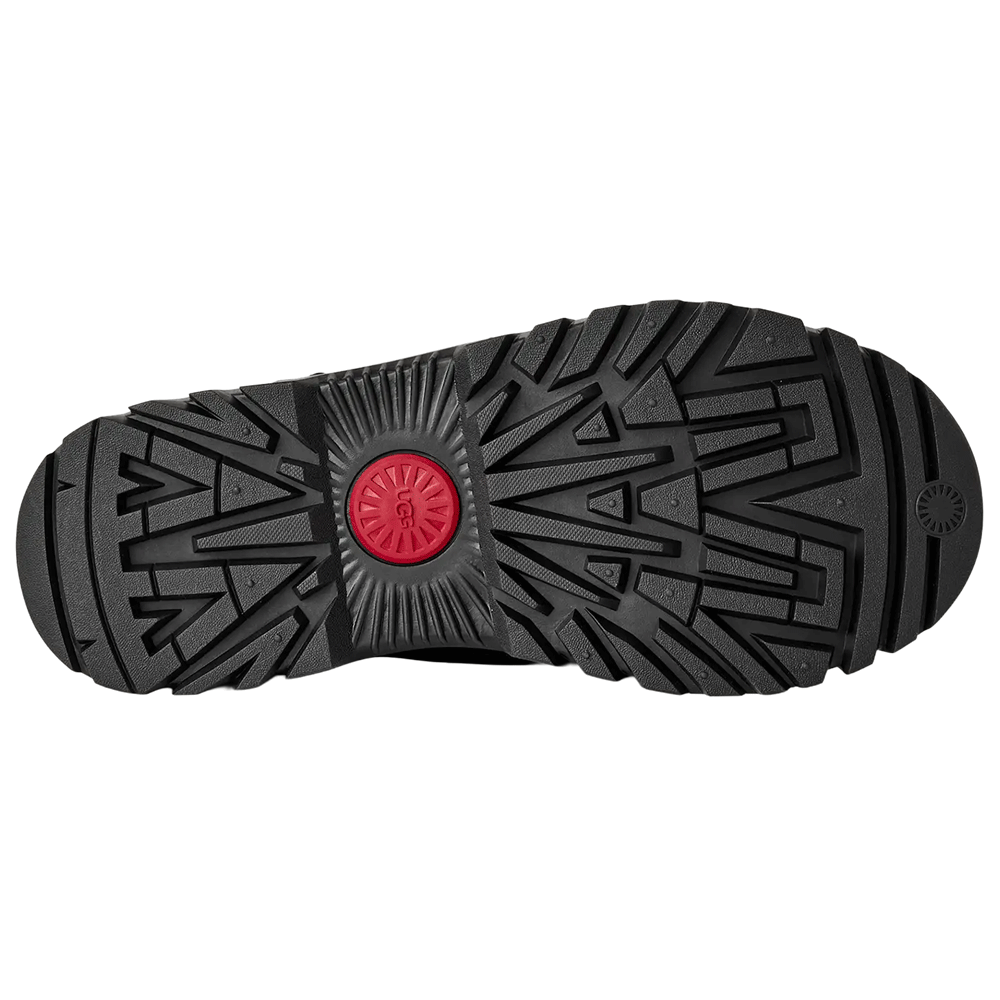 Bottom view of the black UGG Classic Tall TrailGazer boot, showcasing the aggressive black White Spider Rubber® outsole tread pattern with a prominent red UGG logo center plug.