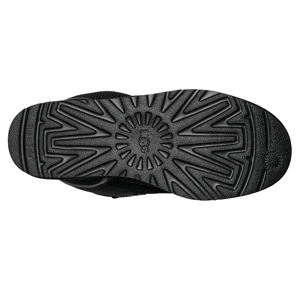 Bottom view of the black UGG Lowmel outsole, showing the ridged, circular traction pattern and the UGG logo at the center.