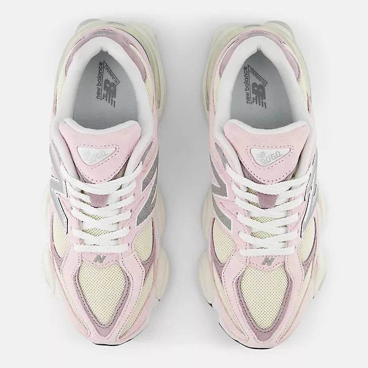 A top-down view of a pair of New Balance 9060 unisex sneakers in pink and cream. The image shows the white laces, the "9060" branding on the tongue, the grey New Balance logo on the mesh toe box, and the "New Balance Running" logo printed on the grey insoles.