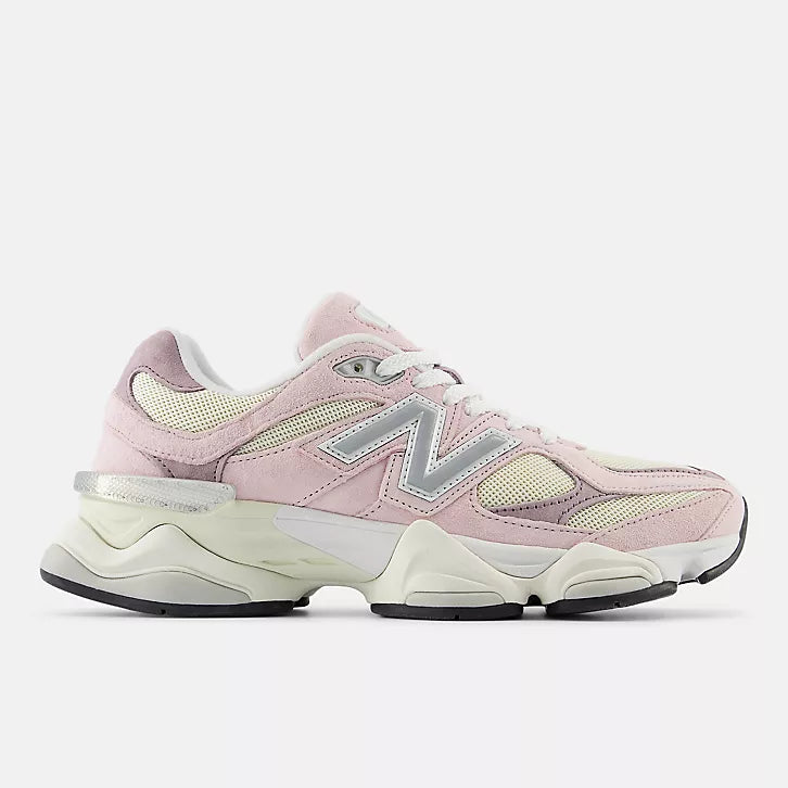 A side profile view of the New Balance 9060 unisex sneakers in a light pink and cream colorway. The shoe features a chunky, futuristic wavy midsole, soft pink suede overlays on cream mesh, and the iconic silver "N" logo on the side.