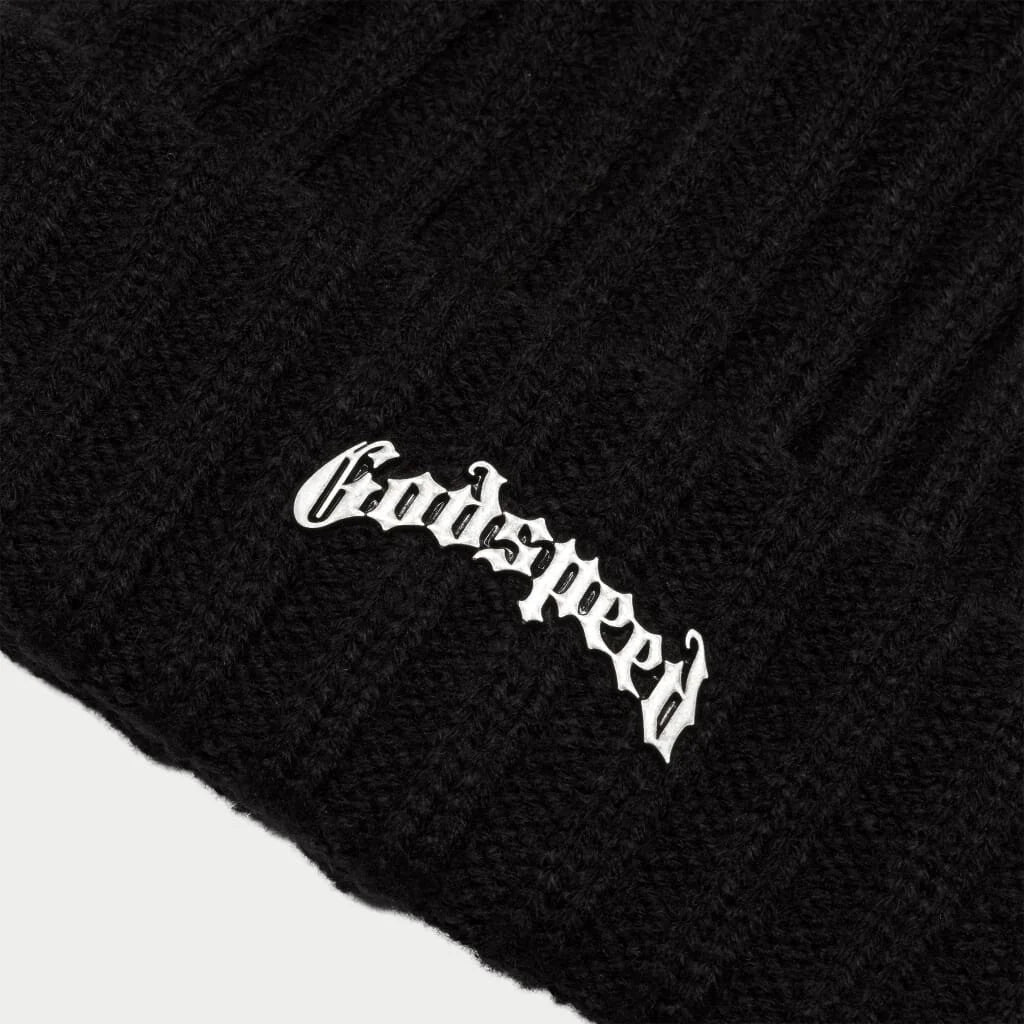 A close-up, high-quality shot of the "Godspeed" beanie's logo. The white embroidery of the stylish, gothic font stands out against the textured black knit of the hat.