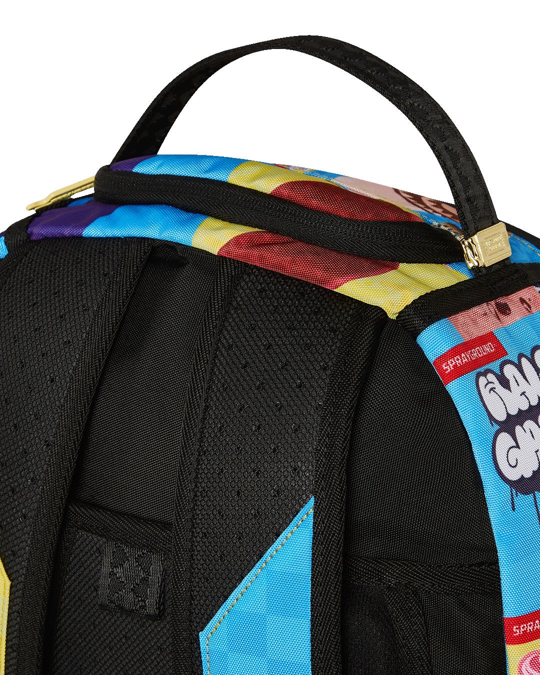 A close-up of the top portion of a black Sprayground backpack. The image shows the padded black handle and the top of the bag, which is covered in a colorful cartoon ice cream menu graphic with a checkered pattern. A small gold-toned metal tag with the Sprayground logo is attached to the base of the handle. The black, padded back panel and shoulder straps are also visible.