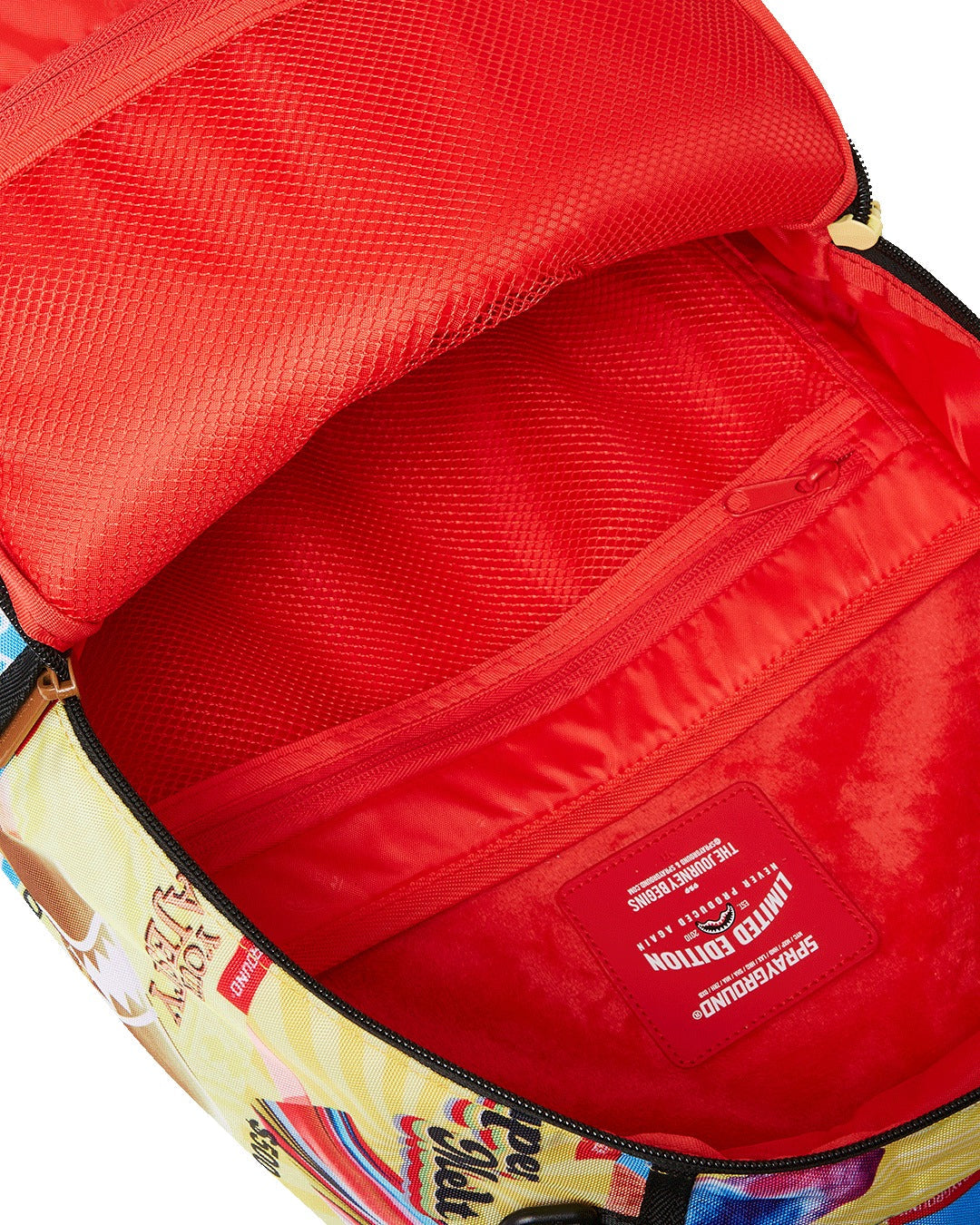 A close-up, internal view of the main compartment of a vibrant Sprayground backpack. The interior is bright red with multiple pockets. On the inside of the front flap, there is a large, red mesh zippered pocket, and below it, a smaller red mesh pocket. The back wall of the compartment has a fleece-lined pocket. A red, rectangular tag with a shark mouth logo reads "LIMITED EDITION" and "SPRAYGROUND" in white lettering. The outside edge of the backpack is visible, featuring a colorful ice cream menu graphic.