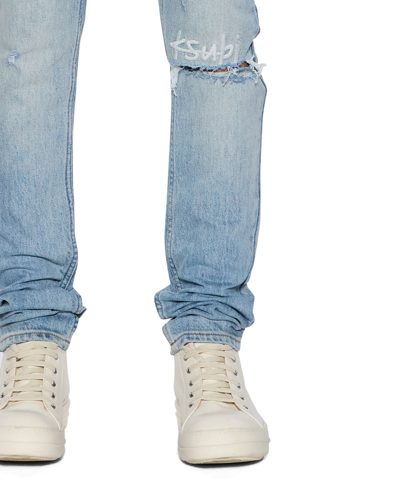 Light blue jeans with a ksubi logo worn by a person on a white background