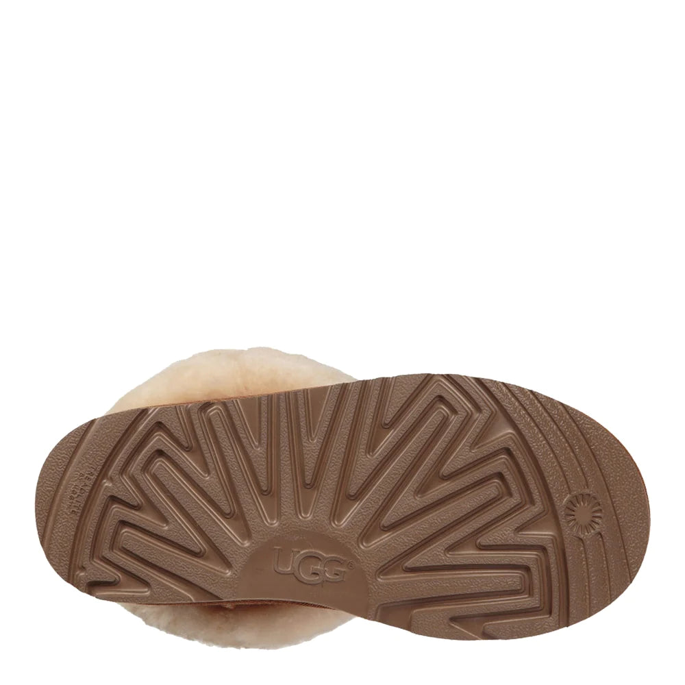 Bottom view of the outsole of a UGG Kid's Classic II boot in brown, showing the deep, molded tread pattern and the plush white sheepskin lining at the cuff.