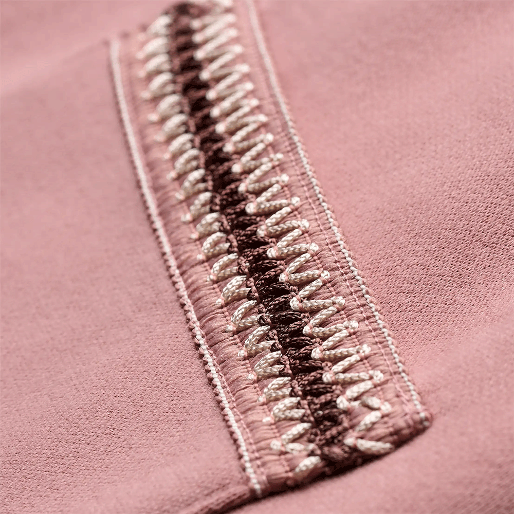 Extreme close-up of the multi-colored braided trim detail, showing inner brown weave and outer white looped stitching on the dusty rose fabric.