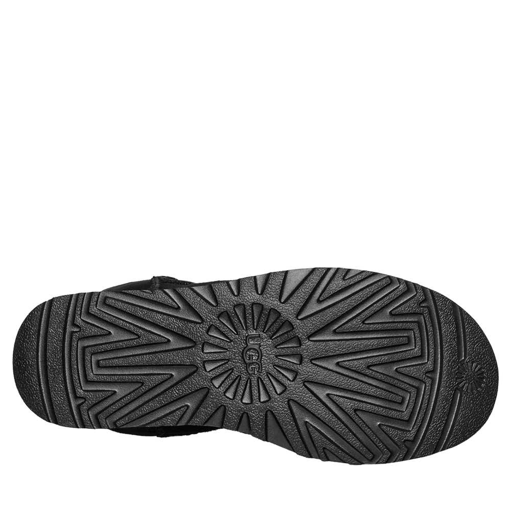 Bottom view of the black UGG Women’s Classic Short II boot, showing the dark, patterned Treadlite sole with the UGG logo in the center.