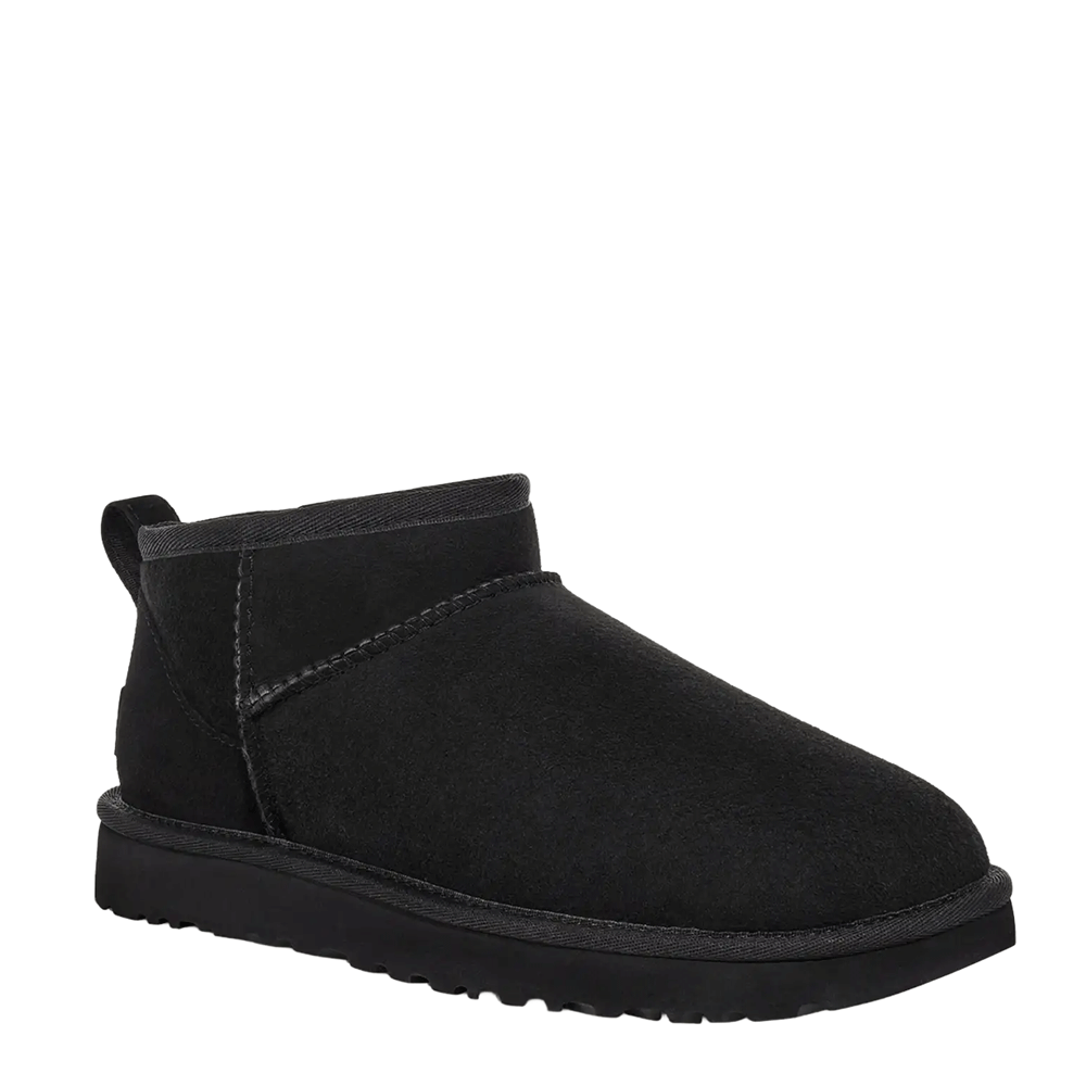 Angled side-view studio shot of a single UGG Women's Classic Ultra Mini boot in black. The extremely low-cut shaft and toe box are prominently displayed, highlighting the smooth black suede material and the chunky black platform sole.