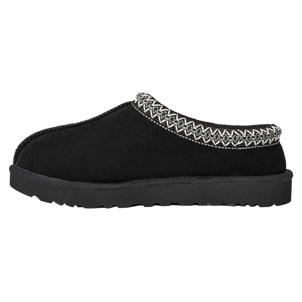Side view of the black UGG Tasman II slipper, showing the full profile of the suede upper, the zig-zag pattern of the grey and white UGGbraid collar, and the thick, black Sugarcane EVA outsole.