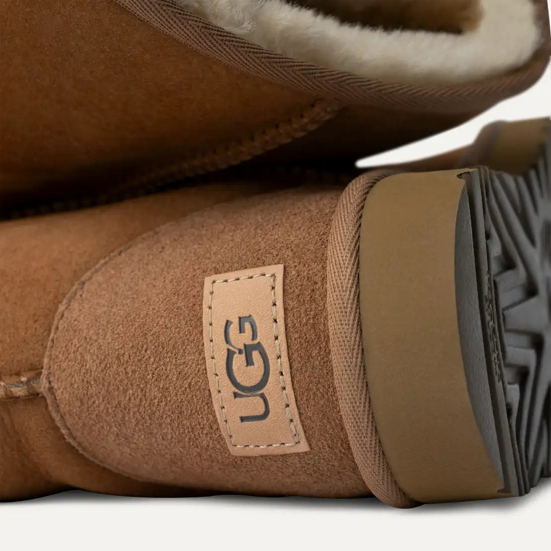 Close-up of brown UGG boots with a visible brand label on a white background