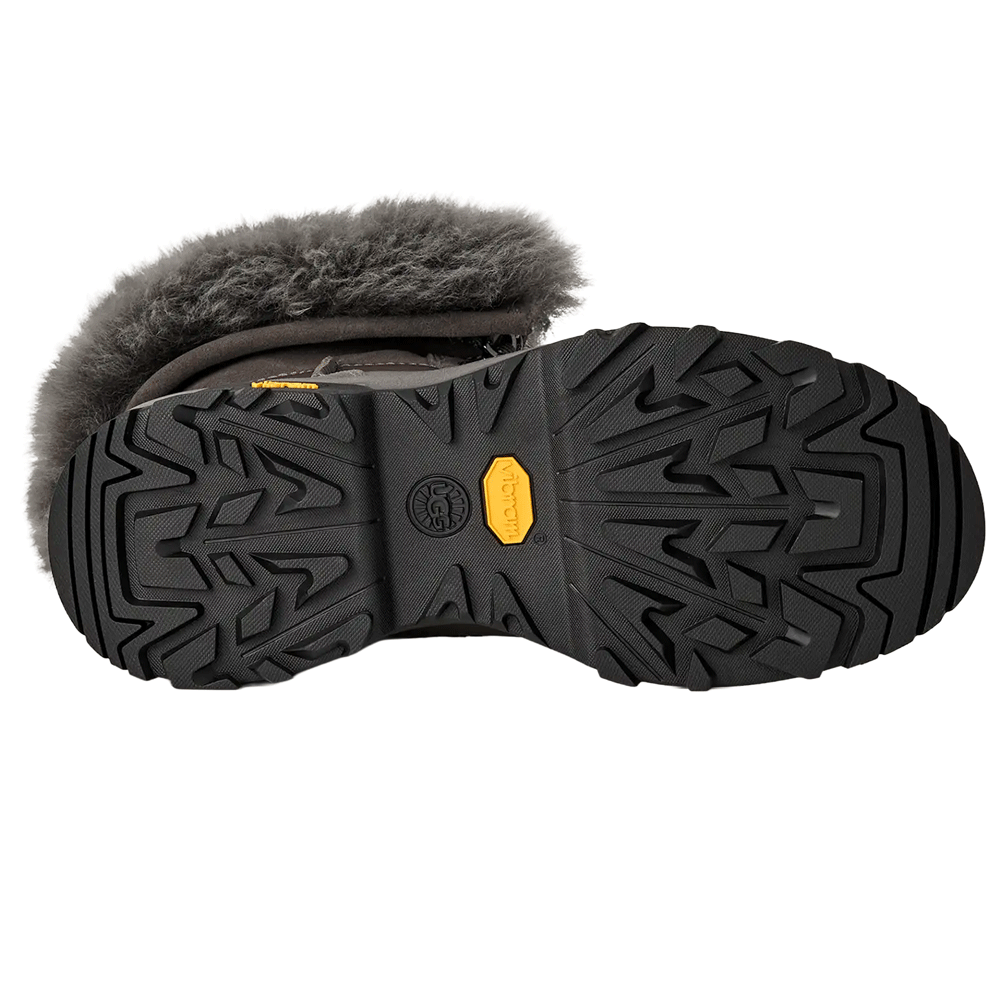 Bottom view of the UGG boot, showcasing the heavy-duty black Vibram rubber outsole with deep, aggressive treads and the prominent yellow Vibram logo for enhanced traction.