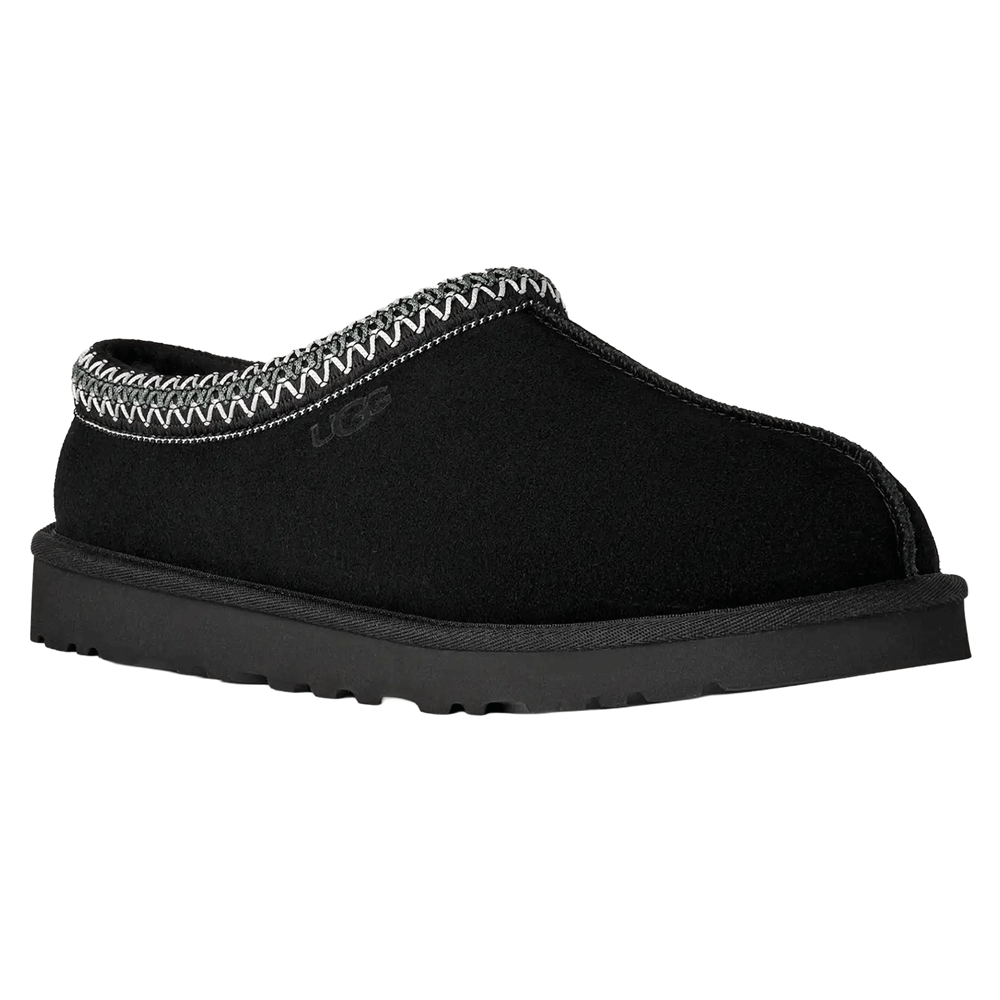 Angled view of the black UGG Tasman II slipper. The suede upper, black Sugarcane EVA outsole, and the gray and white zig-zag UGGbraid trim around the collar are clearly visible.