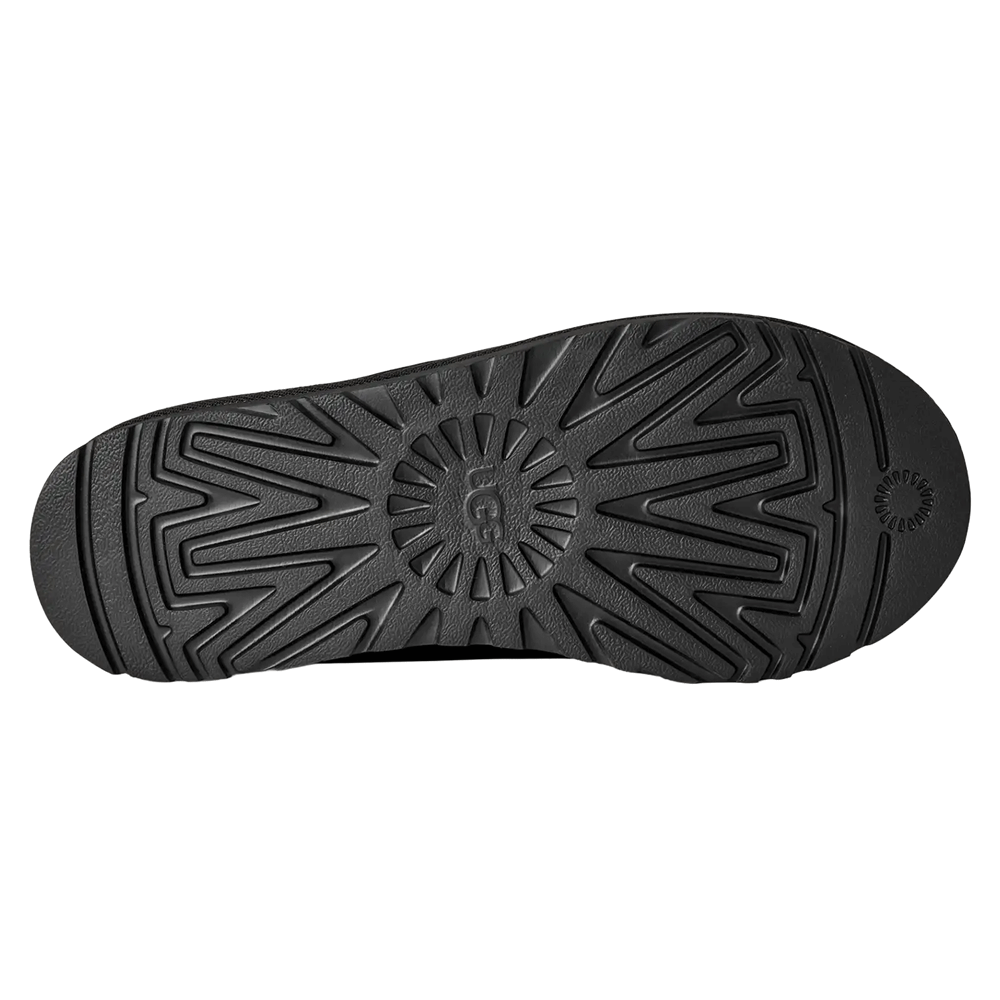 Bottom view of the black UGG Tasman II slipper's outsole. The image shows the full length of the black Sugarcane EVA outsole, featuring a deep, starburst-like traction pattern with a debossed UGG logo in the center.