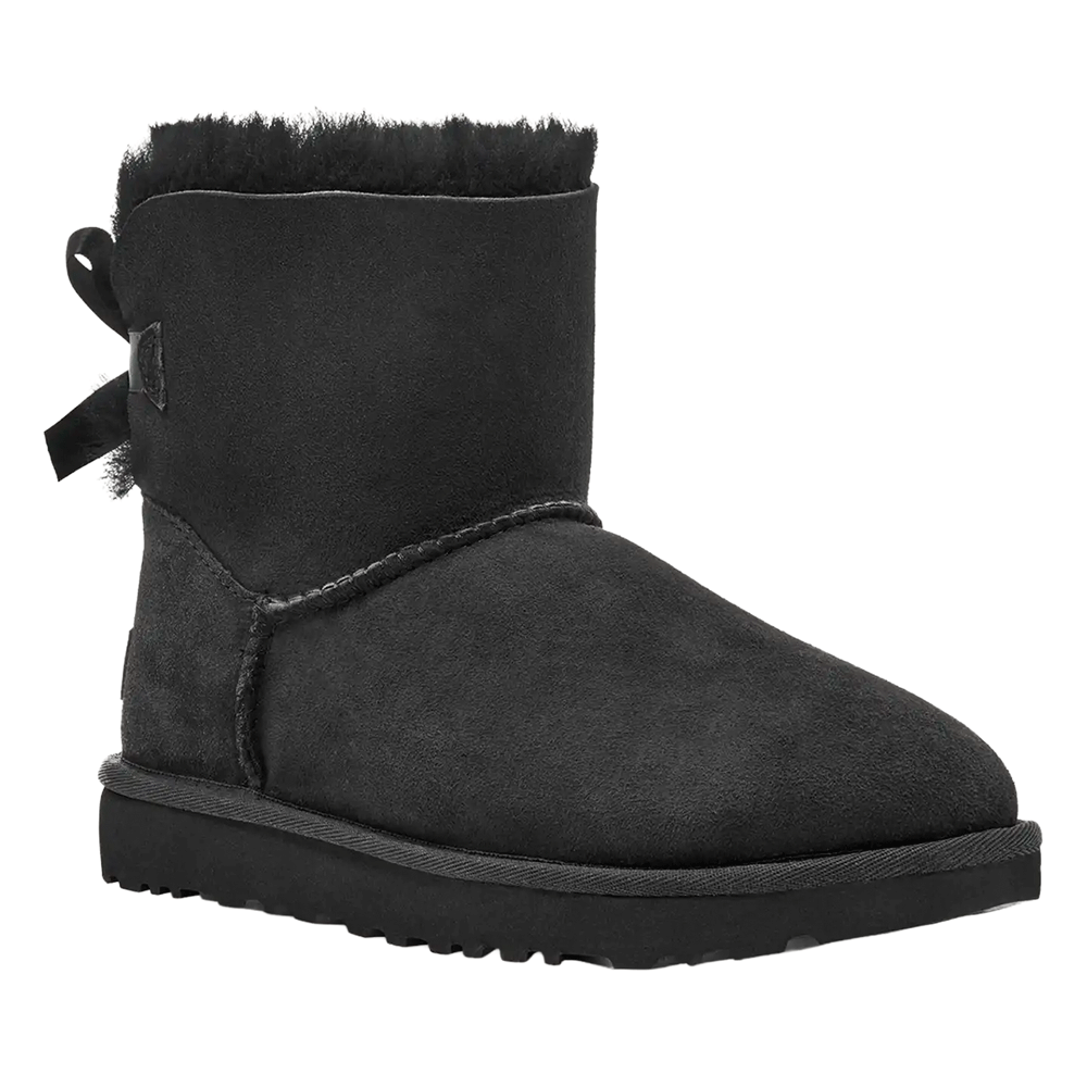 Side/Front view of the Black UGG Mini Bailey Bow II boot, featuring a short black Twinface sheepskin shaft, a plush black fur cuff, a subtle black bow at the back, and a durable black Sugarcane EVA or Treadlite outsole.
