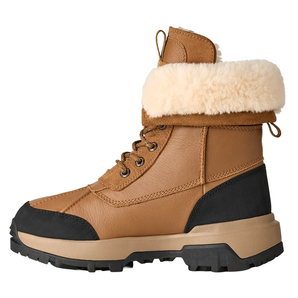 Side view of the Chestnut UGG Adirondack Boot XXV, featuring a waterproof leather upper, a cuffable shaft with a cream-colored fur lining, black leather accents, and a rugged black and beige Vibram outsole.
