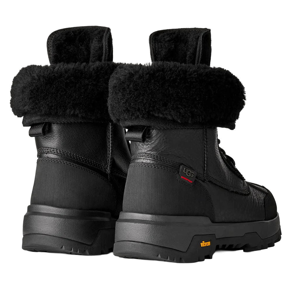 Rear view of a pair of Black UGG Adirondack Boot XXV winter boots, showcasing the thick black fur cuffs, waterproof leather heel panels, and the rugged black Vibram outsole.