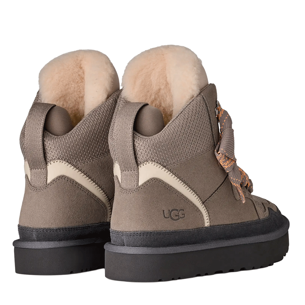 Rear view of the Cobble Grey UGG Highmel high-top sneakers, showing the light-colored UGGplush lining, the suede heel panel with the embossed UGG logo, and the gray webbed pull tabs.