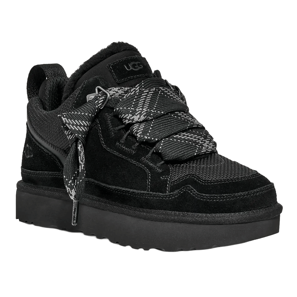 Angled front view of the black UGG Lowmel sneaker. It features a black suede and mesh upper, a thick black Sugarcane EVA outsole, and is laced with loose, oversized two-tone plaid-patterned laces. The dark, cozy collar lining is visible at the ankle.