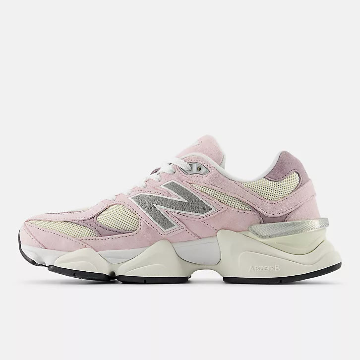 Medial side view of the New Balance 9060 unisex sneakers in pink and cream. This view highlights the stylized grey "N" logo on the inner side, the "ABZORB" branding on the chunky cream midsole, and the textured suede and mesh paneling.