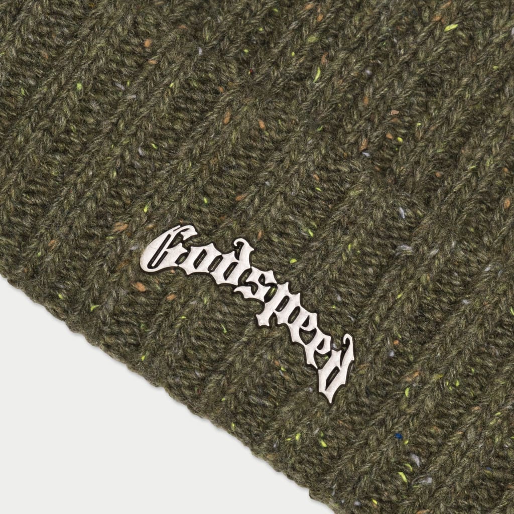 A close-up of a comfortable and stylish olive green beanie, showing the detailed ribbed knit and the white embroidered "Godspeed" logo. The multicolored speckles are also visible, adding a unique touch to the beanie.
