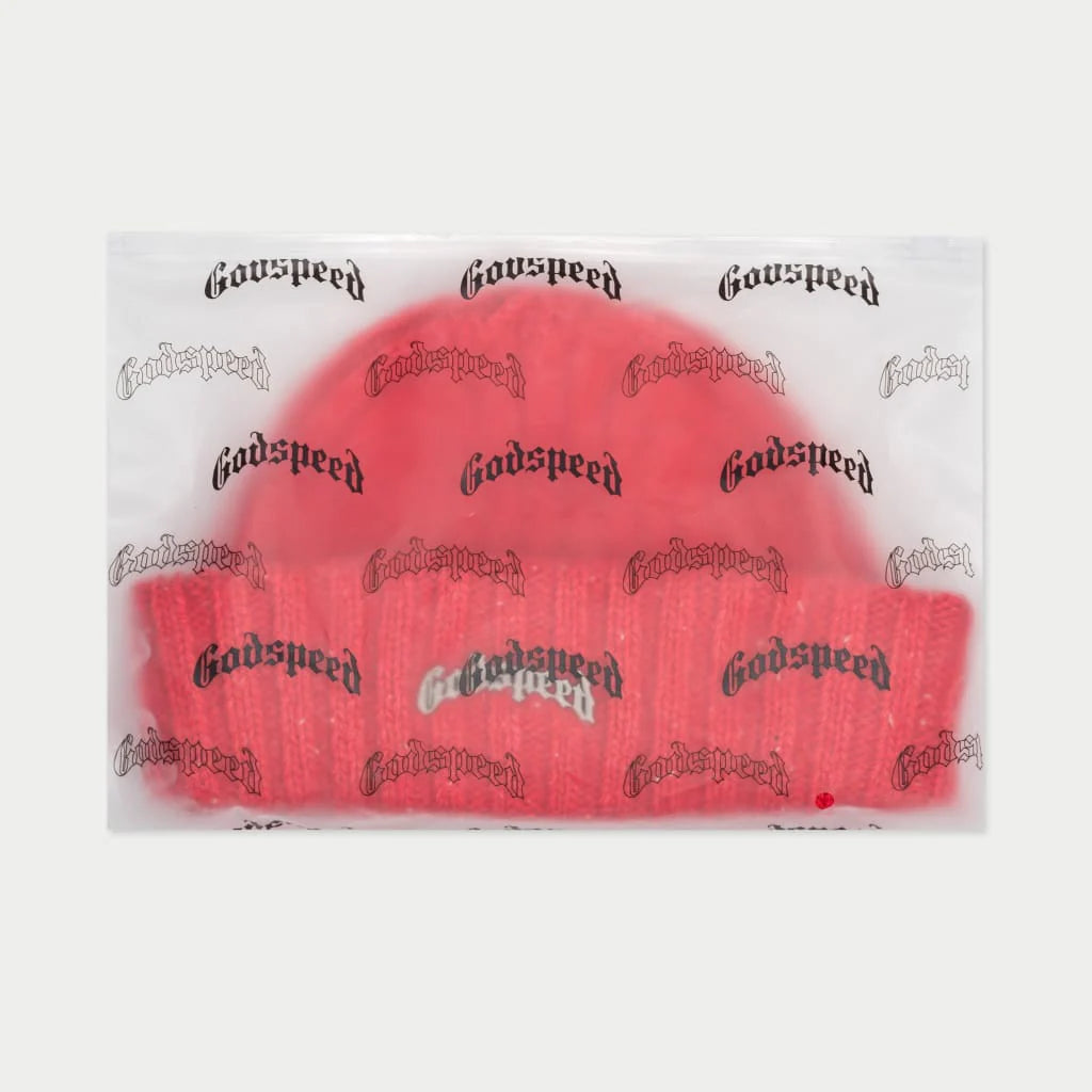 A vibrant red beanie with white speckles, packaged in a clear plastic bag with the brand name "Godspeed" printed in a repeating pattern.