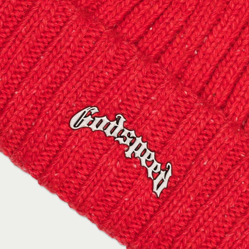 A close-up shot of a vibrant red ribbed beanie with white speckles, showing the detailed embroidery of the "Godspeed" logo on the folded cuff.