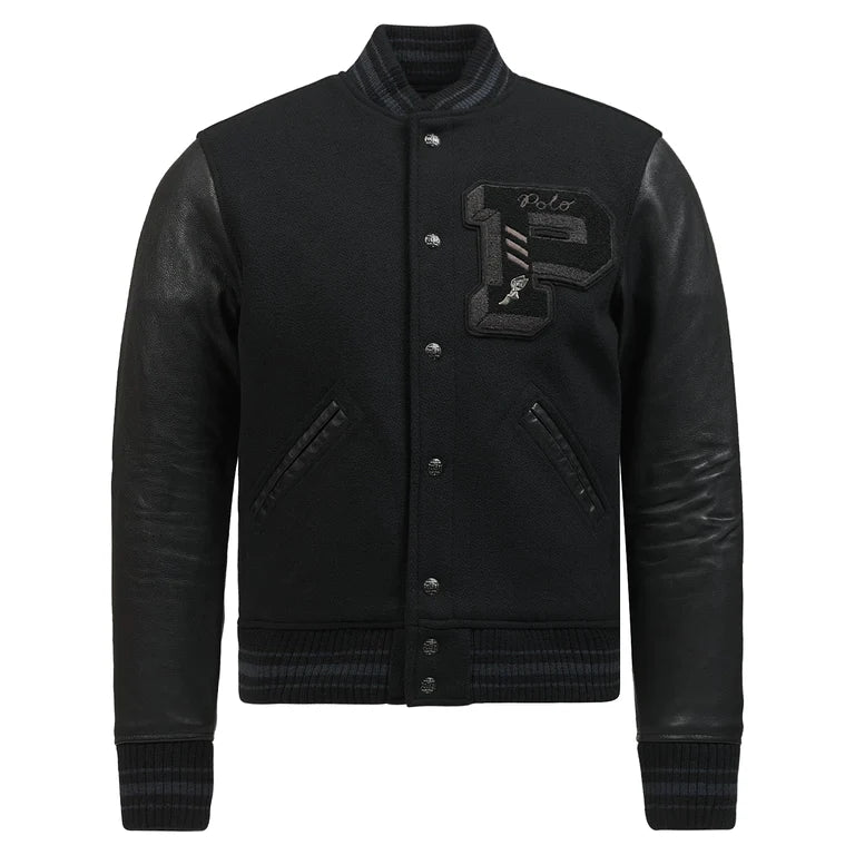 Front view of the Polo Ralph Lauren Iconic Letterman Jacket in an all-black colorway. The jacket features a wool-blend body, genuine leather sleeves, and a large chenille "P" patch with "Polo" embroidery on the left chest. It includes a snap-button front, striped ribbed collar, cuffs, and hem, and two leather-trimmed welt pockets.